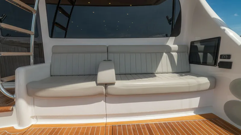 Slide: The Image of Aft Deck Seating Area This image showcases the elegant aft deck seating area of the 2024 Viking 64 Convertible. The space features plush, light-colored upholstered seating, perfectly situated against the glossy teak decking, providing a comfortable and inviting atmosphere. The - 7162579