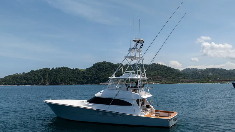 Slide: The Image of Profile View of Sportfishing Yacht This image showcases the sleek profile of the 2024 Viking 64 Convertible, named 'Fish Tank'. The vessel's striking design features a commanding tuna tower, ideal for sportfishing enthusiasts. The spacious aft deck offers ample space for fishing activities - 7162612