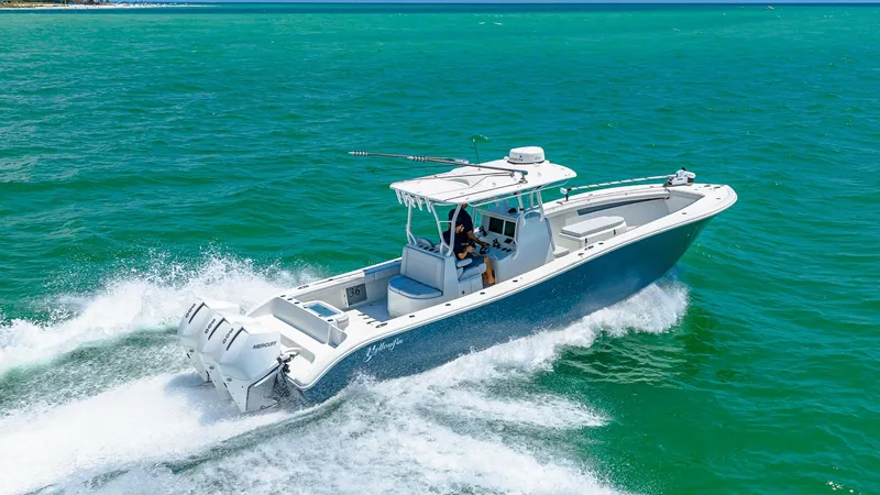 Slide: The Image of Aerial View of 36 Offshore Running The 2021 Yellowfin 36 Offshore is captured in action, slicing through vibrant turquoise waters. This powerful center console features sleek lines and a spacious deck, equipped with high-performance triple outboard engines. Its sturdy T-top and advanced na - 7150933