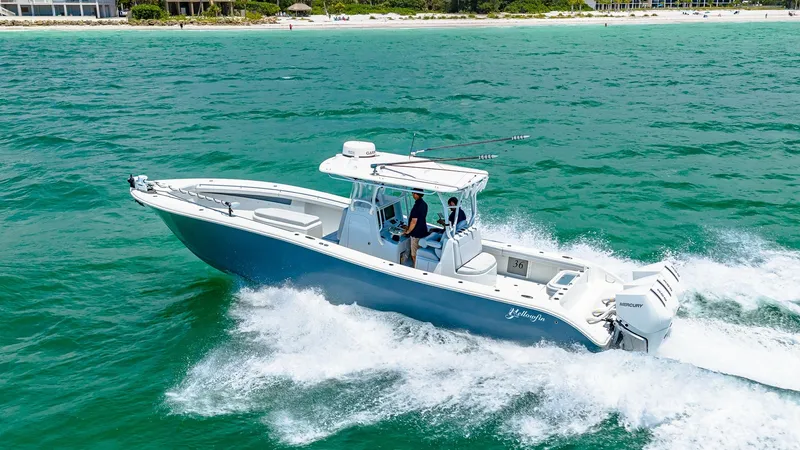 Slide: The Image of Side View of Yellowfin 36 Offshore This image showcases the sleek design of the 2021 Yellowfin 36 Offshore cruising along the coast. The boat features a spacious deck with ample seating and a robust center console for optimal navigation. Its powerful outboard engines provide impressive spe - 7150931