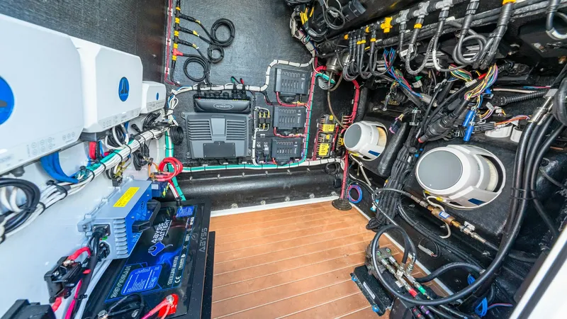 Slide: The Image of Engine Room with Electrical Systems The image showcases the engine room of the 2021 Yellowfin 36 Offshore, highlighting its advanced electrical systems. Visible are meticulously organized wiring and high-quality battery setups, ensuring reliable performance. The clean, well-arranged layout - 7150914