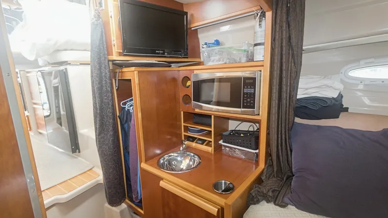 Slide: The Image of Cozy Galley and Sleeping Quarters This inviting space features a compact galley with a built-in microwave and sink, perfect for meal preparation on the go. The adjacent sleeping area offers comfort with plush bedding and ample storage, ensuring a restful experience. Warm wood finishes and - 7180677