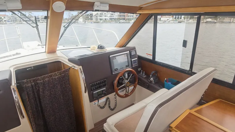 Slide: The Image of Helm Station with Panoramic Views The helm station of the 2014 Cutwater 28 Downeast offers a commanding view with large windows for excellent visibility. The wooden steering wheel and modern navigation equipment provide a blend of classic and contemporary design. A comfortable bench seat - 7180675