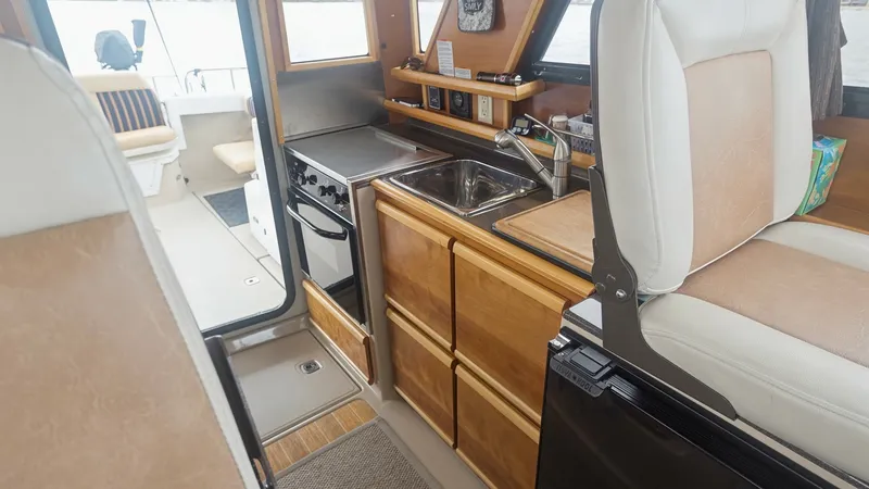 Slide: The Image of Compact Galley with Helm Seating The galley of the 2014 Cutwater 28 Downeast features a sleek, efficient design with rich wood cabinetry and modern appliances. A stainless steel sink and compact stove are complemented by ample storage, optimizing the space for culinary convenience. Adjac - 7180673