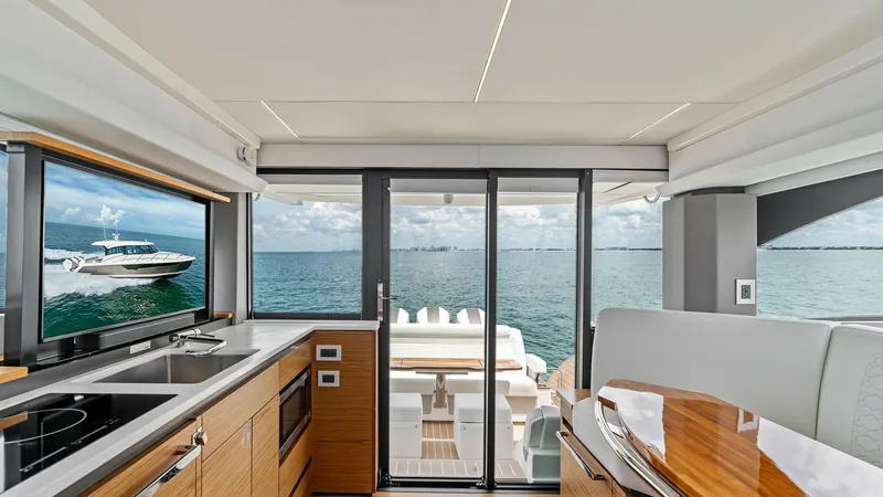 Slide: The Image of Galley and Aft Deck View This image showcases the modern galley of the 2025 Tiara Yachts 48LE, featuring sleek cabinetry and integrated appliances. The open layout provides seamless access to the aft deck, where a comfortable seating area awaits, perfect for alfresco dining. Larg - 7403638