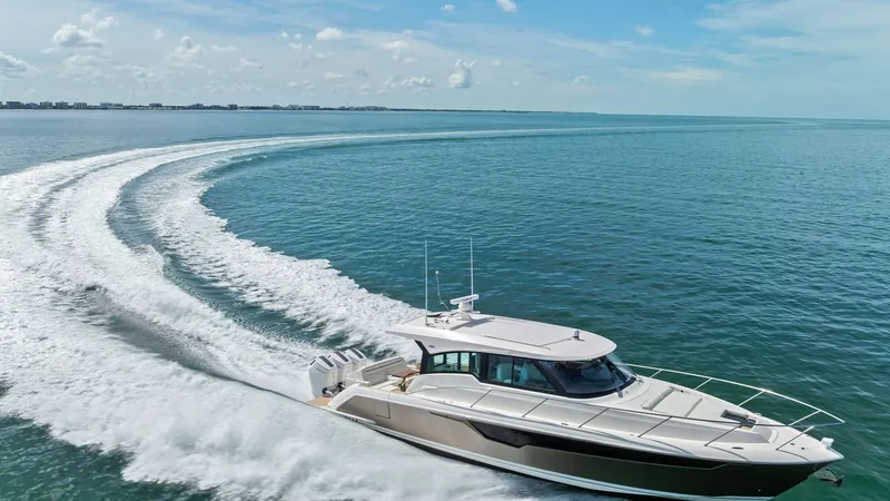 Slide: The Image of Aerial View of Tiara 48LE in Motion The 2025 Tiara Yachts 48LE showcases its sleek design and powerful performance as it glides effortlessly across the open water. The aerial view highlights the vessel's elegant lines and sophisticated exterior, accentuated by the pristine sea backdrop. Wit - 7403670