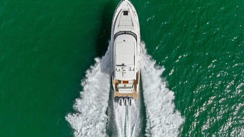 Slide: The Image of Aerial View of Tiara 48LE Underway This striking aerial shot captures the Tiara Yachts 48LE gliding effortlessly through the water, showcasing its sleek design and powerful outboard engines. The vessel's streamlined hull and spacious deck layout are visible, highlighting its modern enginee - 7403666