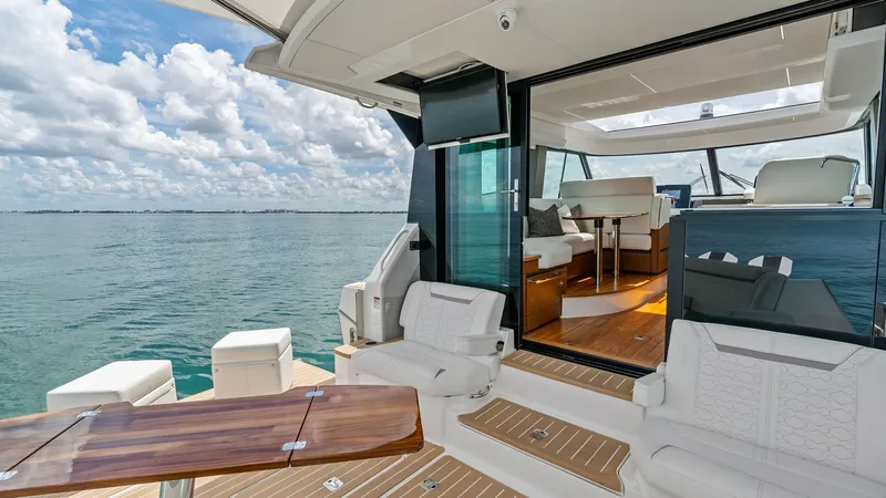 Slide: The Image of Spacious Aft Deck with Seating This inviting aft deck features plush, white seating and a stylish teak table, perfect for alfresco dining or relaxing while enjoying the sea view. The space seamlessly connects to the interior, highlighted by large sliding glass doors that enhance the op - 7403607