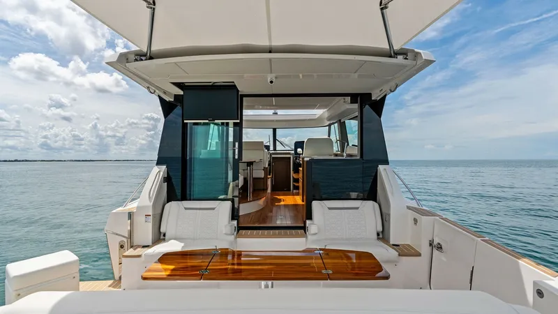 Slide: The Image of Spacious Aft Deck with Seating The Tiara Yachts 48LE's aft deck offers a spacious and inviting area perfect for relaxation and entertainment. Featuring plush, white seating and a beautifully crafted wooden table, the space is elegantly designed for comfort and functionality. With an ex - 7403608
