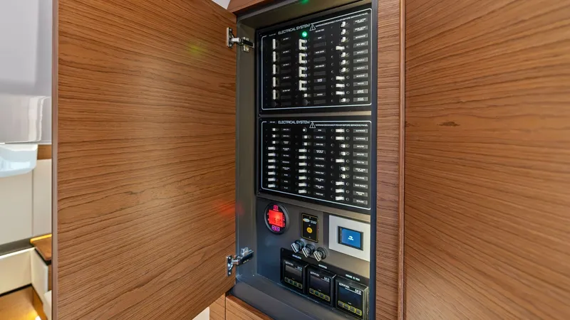 Slide: The Image of Electrical Control Panel This image showcases the modern electrical control panel of the 2025 Tiara Yachts 48LE. The panel is neatly housed within a sleek wooden cabinet, reflecting the yacht's commitment to both functionality and aesthetic appeal. Its intuitive layout ensures ea - 7403659
