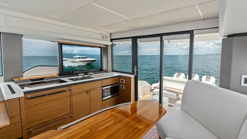 Slide: The Image of Contemporary Interior Salon with Ocean View This elegant interior salon of the 2025 Tiara Yachts 48LE showcases a seamless blend of luxury and function. Featuring sleek cabinetry and a polished wood dining table, the space is designed for both comfort and style. Expansive windows and sliding glass - 7403641