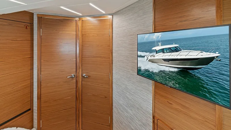 Slide: The Image of Luxurious Cabin with TV Display This elegant cabin in the 2025 Tiara Yachts 48LE features warm wood finishes and a sleek modern design. A large flat-screen TV is mounted on the wall, providing entertainment with a view of the sea. The space is accented by contemporary lighting, enhancin - 7403645