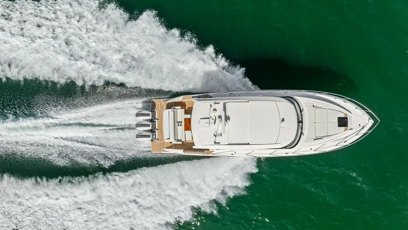 Slide: The Image of Aerial View of Tiara 48LE in Motion This stunning aerial shot captures the sleek design of the 2025 Tiara 48LE as it glides through the water. The vessel's powerful outboard engines create an impressive wake, highlighting its performance capabilities. The spacious aft deck offers ample seat - 7403667