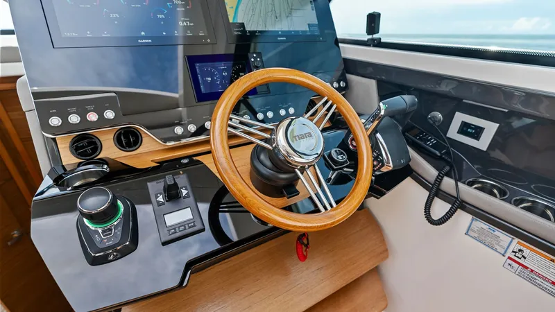 Slide: The Image of Modern Helm with Advanced Navigation The helm of the 2025 Tiara Yachts 48LE showcases state-of-the-art navigation technology with dual multifunction displays and intuitive controls. A polished wooden steering wheel complements the sleek, high-gloss dashboard, offering both functionality and - 7403633