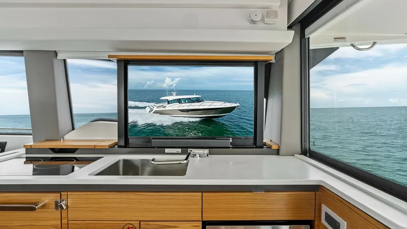 Slide: The Image of Galley with Ocean View Window The galley of the 2025 Tiara Yachts 48LE features sleek cabinetry and a modern sink, providing functionality and style. Ample natural light floods the space through expansive windows, offering breathtaking ocean views that enhance the cooking and dining e - 7403627