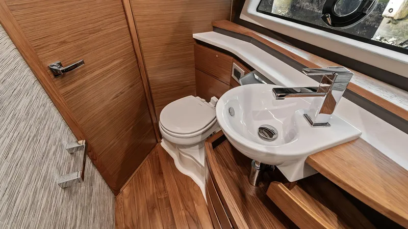 Slide: The Image of Elegant Yacht Head with Modern Fixtures This well-appointed yacht head features sleek modern fixtures and warm wood finishes, creating a luxurious and inviting space. The contemporary sink and faucet complement the stylish cabinetry, while the large window allows natural light to enhance the ro - 7403648