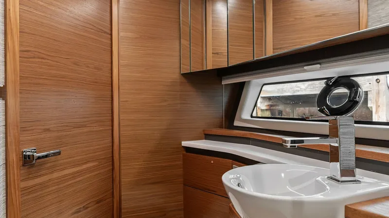 Slide: The Image of Elegant Vanity in Guest Head This sophisticated guest head features a sleek vanity with a modern vessel sink and polished chrome fixtures. The warm wood finishes and mirrored cabinetry create a luxurious atmosphere, while the large window provides natural light and a serene view. The - 7403656