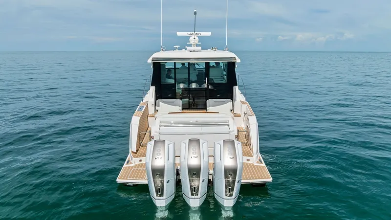 Slide: The Image of Stern View with Triple Outboards This image showcases the sleek stern of the 2025 Tiara Yachts 48LE, featuring powerful triple outboard engines for optimal performance. The expansive swim platform offers easy water access, ideal for leisure activities. Stylish teak decking and clean line - 7403600