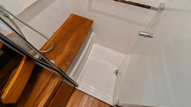 Slide: The Image of Modern Shower with Teak Accents This luxurious shower area in the 2025 Tiara Yachts 48LE features elegant teak flooring and bench, providing both style and functionality. The glass enclosure adds a modern touch, complementing the sleek chrome fixtures. Designed for comfort and convenien - 7403650