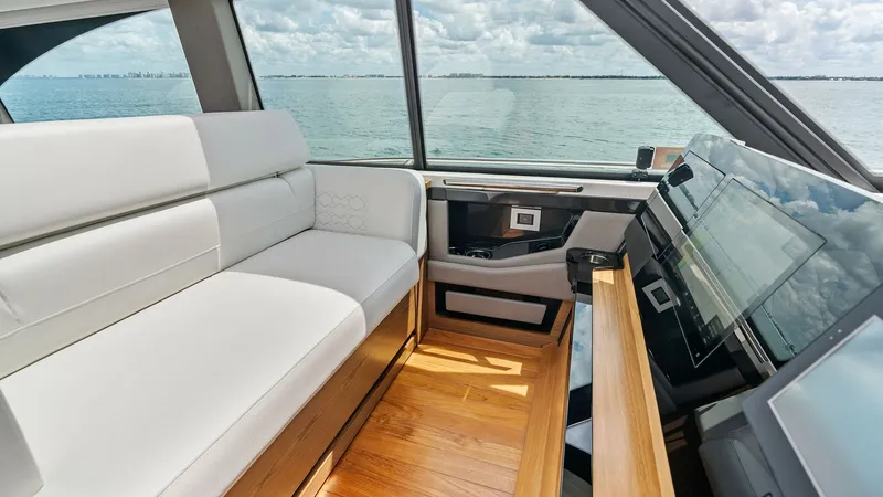 Slide: The Image of Helm Seating Area with Ocean View This elegant helm seating area on the 2025 Tiara Yachts 48LE features plush white upholstery contrasting beautifully with the sleek wooden flooring. Large windows offer panoramic ocean views, creating a bright and inviting atmosphere for both the captain - 7403637