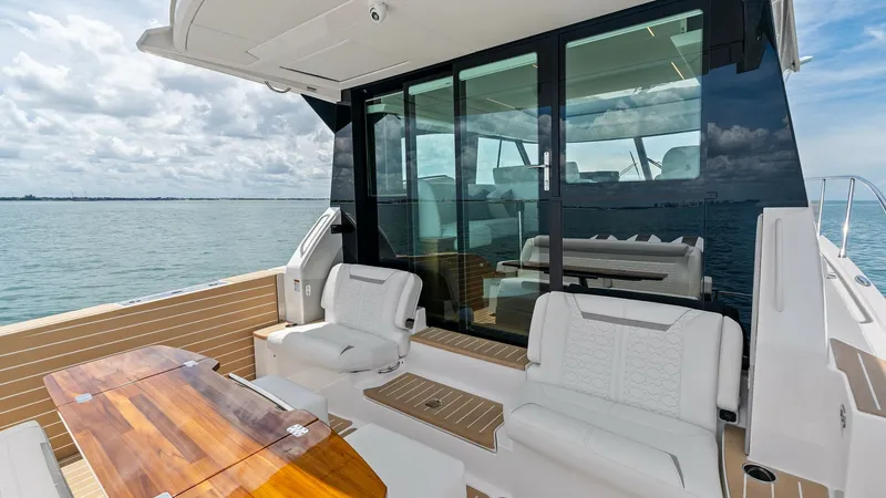 Slide: The Image of Spacious Aft Deck with Seating The aft deck of the 2025 Tiara Yachts 48LE features elegant seating with plush white cushions, perfect for relaxation or entertaining guests. The teak table adds a touch of sophistication, complemented by the durable, stylish flooring. Large sliding glass - 7403606