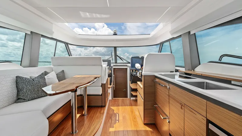 Slide: The Image of Spacious Salon and Helm Station This image showcases the elegant salon and helm station of the 2025 Tiara Yachts 48LE. The space features an open layout with plush seating, a sleek wooden table, and panoramic windows offering stunning ocean views. The modern helm is equipped with advanc - 7403589