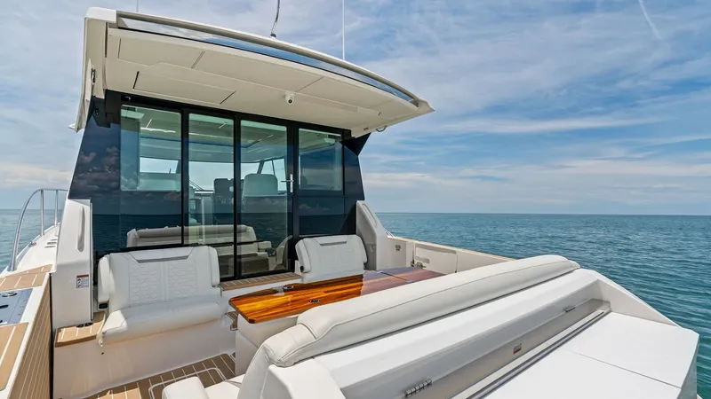 Slide: The Image of Spacious Aft Deck with Seating The 2025 Tiara Yachts 48LE features an expansive aft deck with luxurious seating, perfect for entertaining or relaxing. The space is accentuated by a sleek, modern design and high-quality finishes, including a polished wooden table and comfortable cushion - 7403610