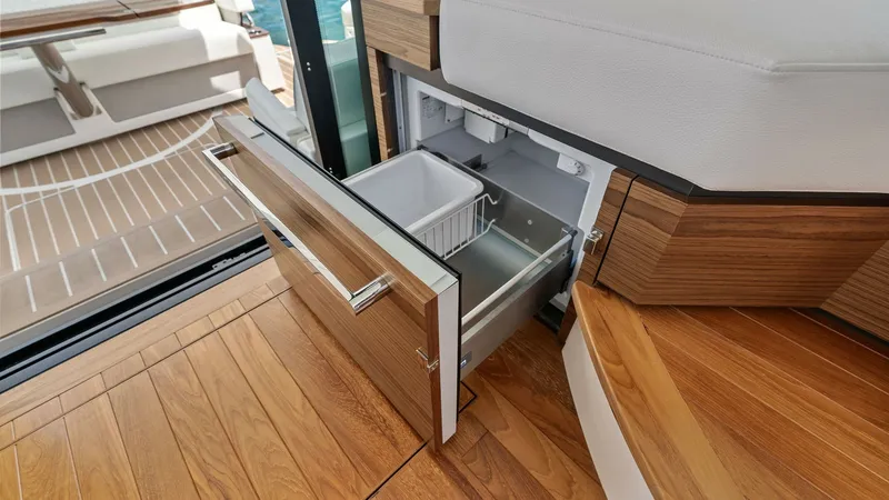 Slide: The Image of Galley Drawer Refrigerator This image showcases the sleek, built-in drawer refrigerator in the galley of the 2025 Tiara Yachts 48LE. The high-quality wood finish complements the luxurious interior design, providing ample storage space for provisions. The adjacent seating area offer - 7403630