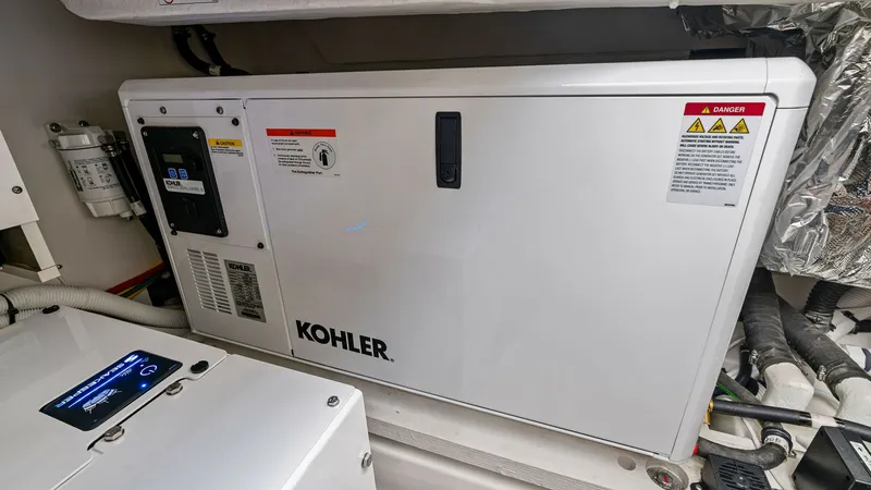 Slide: The Image of Engine Room with Kohler Generator This image showcases the engine room of the Tiara Yachts 48LE, featuring a Kohler generator. The setup highlights the yacht's advanced engineering and efficient power management system. The neatly organized space emphasizes functionality and ease of acces - 7403663