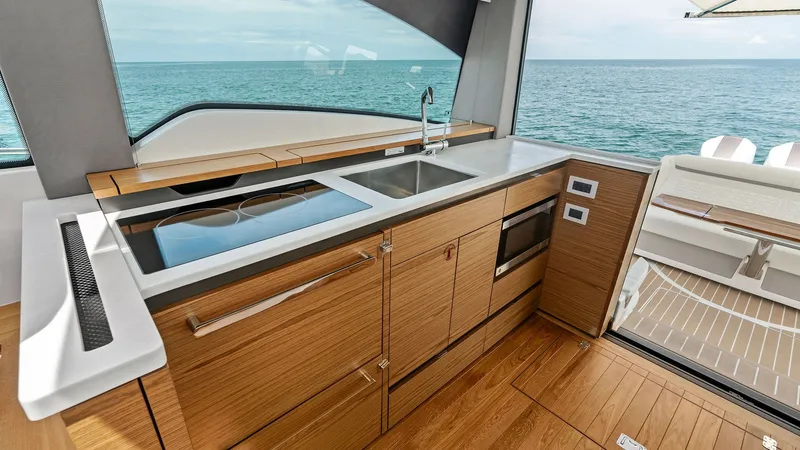 Slide: The Image of Galley with Sea View This modern galley on the Tiara Yachts 48LE boasts sleek wooden cabinetry and integrated appliances, offering both style and functionality. The large window provides a stunning view of the open sea, enhancing the cooking and dining experience. Ample count - 7403628