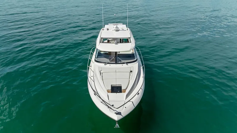 Slide: The Image of Aerial View of Bow and Foredeck This image showcases the sleek bow and spacious foredeck of the 2025 Tiara Yachts 48LE. The clean lines and modern design are accentuated by the yacht's pristine white finish, offering an elegant presence on the water. The foredeck features ample space fo - 7403592