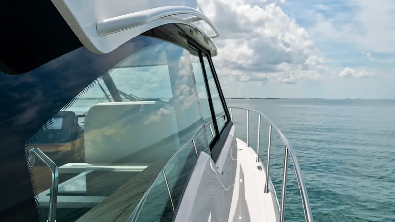 Slide: The Image of Starboard Side Deck View This image captures the sleek starboard side deck of the 2025 Tiara Yachts 48LE. The expansive windows reflect the serene ocean backdrop, enhancing the vessel's modern and elegant design. The stainless steel railing provides both safety and style, perfect - 7403618
