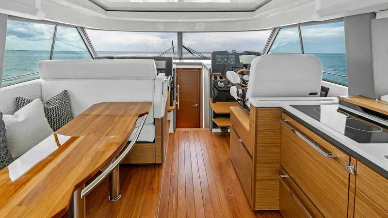 Slide: The Image of Helm and Salon with Panoramic Views The helm and salon area of the 2025 Tiara Yachts 48LE showcases a modern and elegant design. Featuring rich wood flooring and sleek cabinetry, the space offers a luxurious ambiance. Large windows provide panoramic ocean views, while the plush seating and - 7403642
