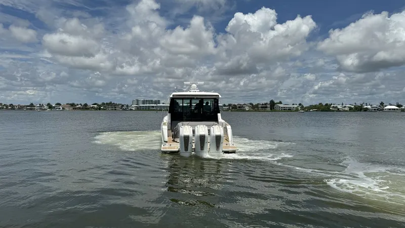 Slide: The Image of Aft View with Triple Outboard Engines The 2025 Tiara Yachts 48LE showcases its robust performance with triple outboard engines, ideal for powerful cruising. The sleek design complements the vessel's cutting-edge technology, providing both efficiency and speed on the water. The scenic backdrop - 7179513