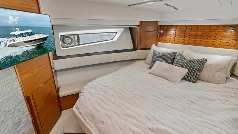 Slide: The Image of Luxurious Master Stateroom The master stateroom of the 2025 Tiara Yachts 48LE exudes comfort and style with a plush, oversized bed complemented by elegant, wooden finishes. Natural light streams through the uniquely shaped window, enhancing the spacious feel and providing stunning - 7403644