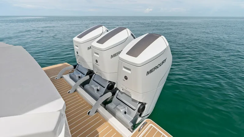Slide: The Image of Triple Outboard Engines on Swim Platform This image showcases the powerful triple Mercury outboard engines on the 2025 Tiara Yachts 48LE. The sleek engines are mounted on a spacious teak swim platform, offering easy access and enhancing the vessel's performance. The setup promises a blend of spe - 7403601