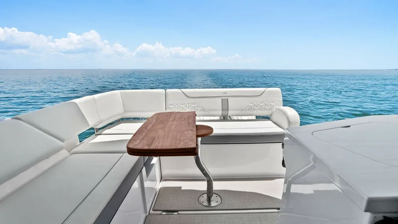 Slide: The Image of Stern Deck with Seating Area The stern deck of the 2025 Regal 38 EXC features a spacious seating area with plush, white upholstered cushions, perfect for relaxation and socializing. A sleek wooden table provides a convenient space for dining or enjoying refreshments with a panoramic - 7180424