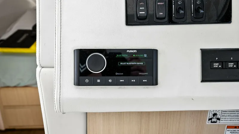 Slide: The Image of Helm Audio Control Panel The helm of the 2025 Regal 38 EXC features a sleek Fusion audio control panel, seamlessly integrated into the console for effortless access. The modern interface allows for easy Bluetooth connectivity, enhancing the onboard entertainment experience. Compl - 7180451