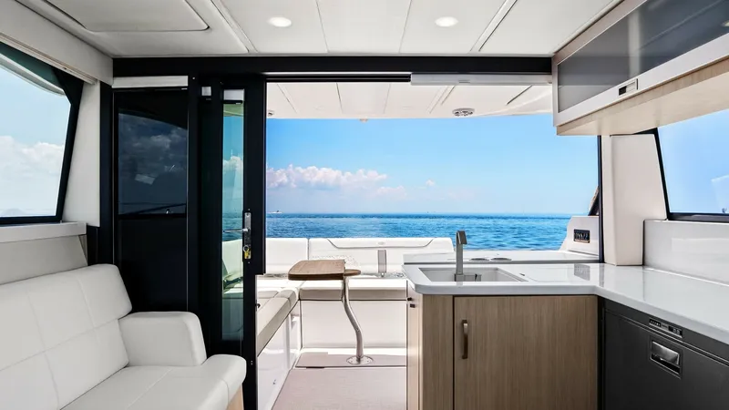 Slide: The Image of Galley and Aft Deck View This image showcases the sleek galley area of the 2025 Regal 38 EXC, seamlessly connected to the aft deck. The galley features modern cabinetry and a polished countertop, providing a functional space for meal preparation. Large sliding glass doors open to - 7180414