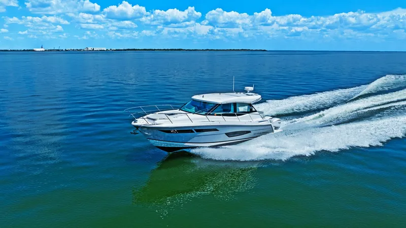Slide: The Image of Dynamic Side View at Sea This image captures the sleek and powerful side profile of the 2025 Regal 38 EXC by Galati Yacht Sales cutting through open waters. The yacht showcases a modern, aerodynamic design with a spacious deck and elegant lines. The vibrant blue sea and clear sky - 7180479