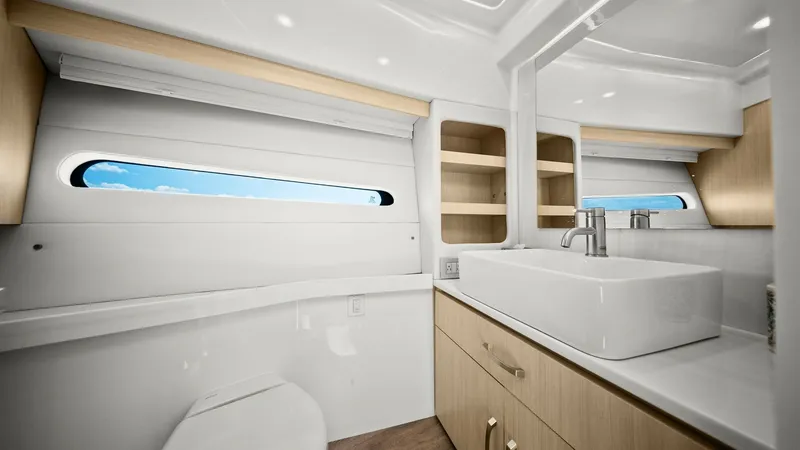Slide: The Image of Modern Ensuite Bathroom with Vanity This elegant ensuite bathroom on the 2025 Regal 38 EXC features a sleek, contemporary design. The space is highlighted by a stylish square basin sink and modern fixtures, set against a backdrop of light wood cabinetry. Natural light pours in through the e - 7180440