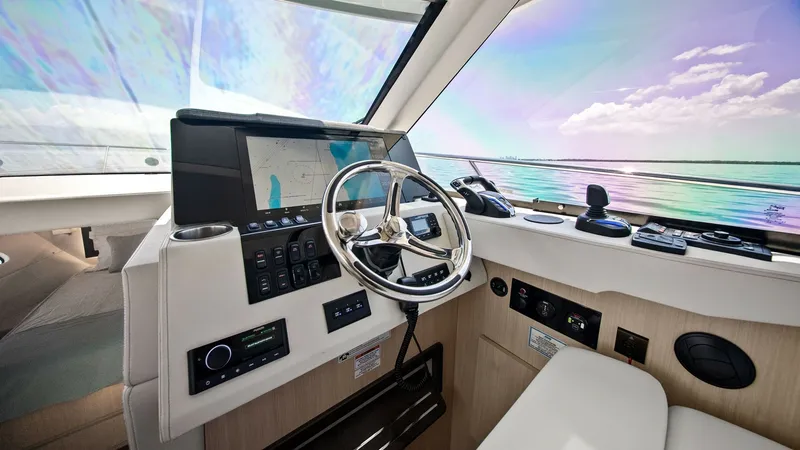 Slide: The Image of Helm Station with Panoramic Views The helm station of the 2025 Regal 38 EXC features a modern, sleek design with state-of-the-art navigation technology. A large touchscreen display and intuitive controls are elegantly integrated into the console, providing easy access for the captain. Exp - 7180435