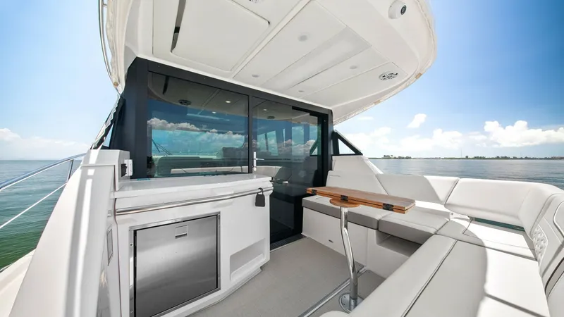 Slide: The Image of Spacious Aft Deck with Wet Bar This inviting aft deck on the 2025 Regal 38 EXC offers a seamless blend of comfort and functionality. Featuring a sleek wet bar with a stainless-steel refrigerator, it's perfect for entertaining guests. The ample seating and elegant wooden table provide a - 7180413