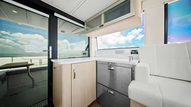 Slide: The Image of Galley with Expansive Views The galley of the 2025 Regal 38 EXC features sleek cabinetry and modern appliances, including a stainless steel refrigerator. The large window and sliding glass door offer stunning panoramic views, enhancing the open and airy feel. The light wood finishes - 7180432