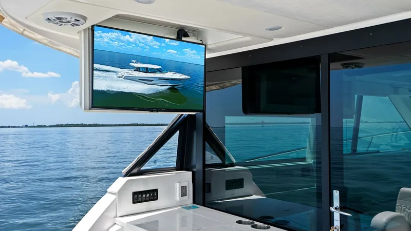 Slide: The Image of Cockpit Entertainment Area with TV This Regal 38 EXC features a stylish cockpit entertainment area, highlighted by a mounted flat-screen TV perfect for alfresco viewing. The sleek design includes a glossy countertop with integrated storage, providing a functional and modern space for relax - 7180420