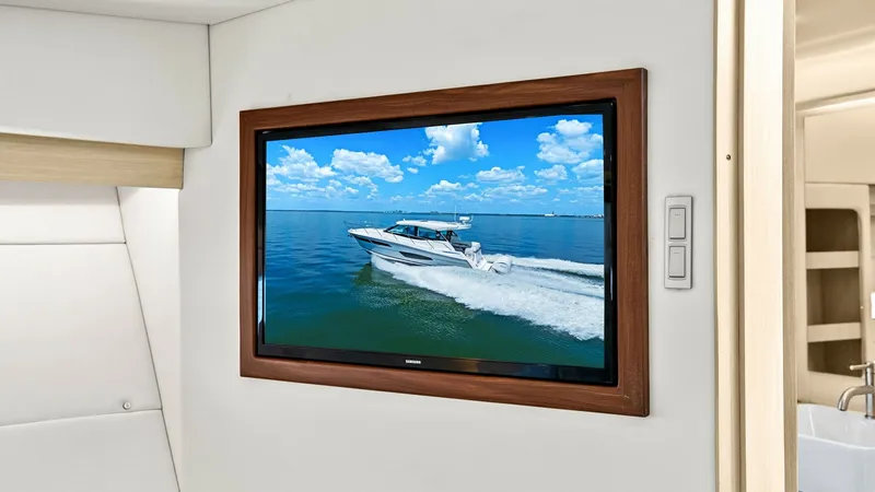 Slide: The Image of Interior Entertainment System Display This image showcases the luxurious interior entertainment system of the 2025 Regal 38 EXC, featuring a sleek, wall-mounted television. The screen is set within a rich wooden frame, contributing to the elegant and modern aesthetic of the space. Adjacent to - 7180437