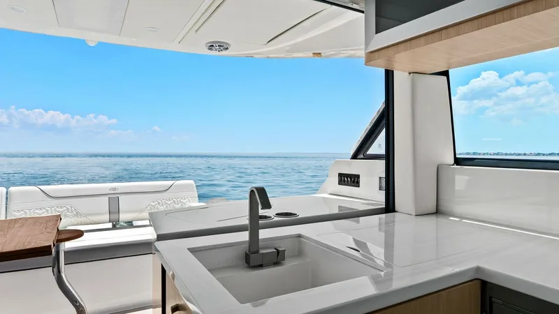 Slide: The Image of Cockpit Galley with Ocean View This image showcases the sleek cockpit galley of the 2025 Regal 38 EXC. Featuring a modern, polished countertop with an integrated sink, the space is designed for convenience and style. The expansive window offers stunning ocean views, creating a perfect - 7180427