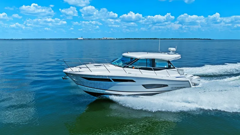 Slide: The Image of Side Profile Cruising at Speed This image showcases the sleek design of the 2025 Regal 38 EXC as it glides across calm waters. The vessel's aerodynamic hull and modern lines are highlighted, emphasizing its speed and elegance. The expansive windows and hardtop add to the luxurious appe - 7180478