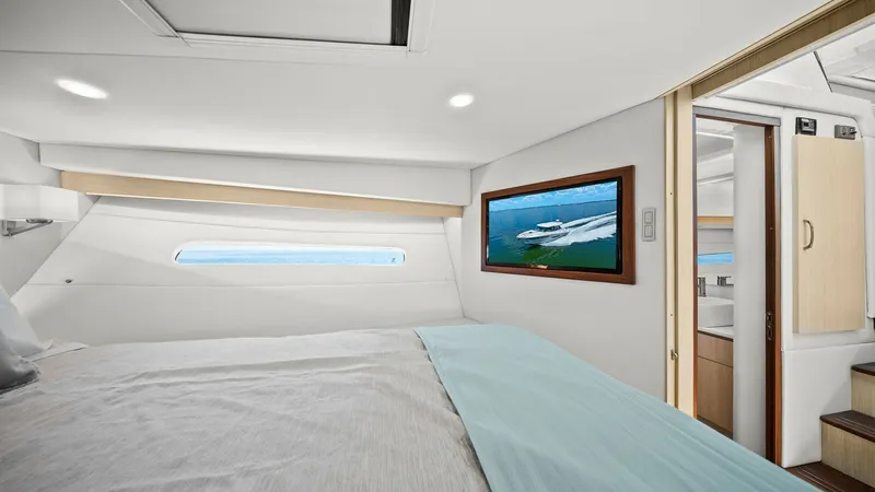 Slide: The Image of Luxurious Master Stateroom This master stateroom on the 2025 Regal 38 EXC offers a serene retreat with its elegant design and spacious layout. The large window provides natural light and stunning ocean views, enhancing the room's airy ambiance. High-quality finishes and a plush bed - 7180436