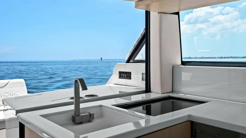 Slide: The Image of Outdoor Galley with Ocean View This outdoor galley on the 2025 Regal 38 EXC offers a sleek and modern design with a spacious countertop and built-in sink. The high-quality finishes include a smooth surface and integrated cooktop, perfect for alfresco dining. Large windows provide a stu - 7180429